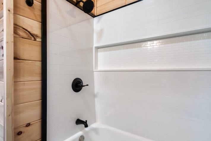 The third-floor ensuite features a clean tiled tub/shower with a built-in niche… Sevierville, Tennessee Cabin Rental - Gallery Image #28