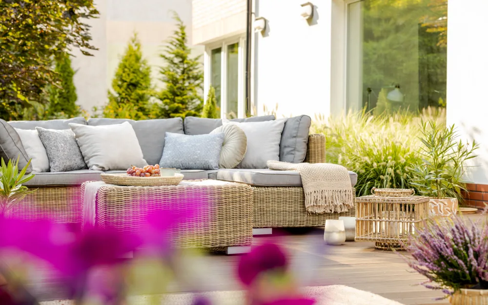 A beautiful outdoor patio setup featuring comfortable chairs, a cozy rug, and decorative pillows, all made with high-quality Sunbrella fabrics that resist fading and damage from sun and rain.