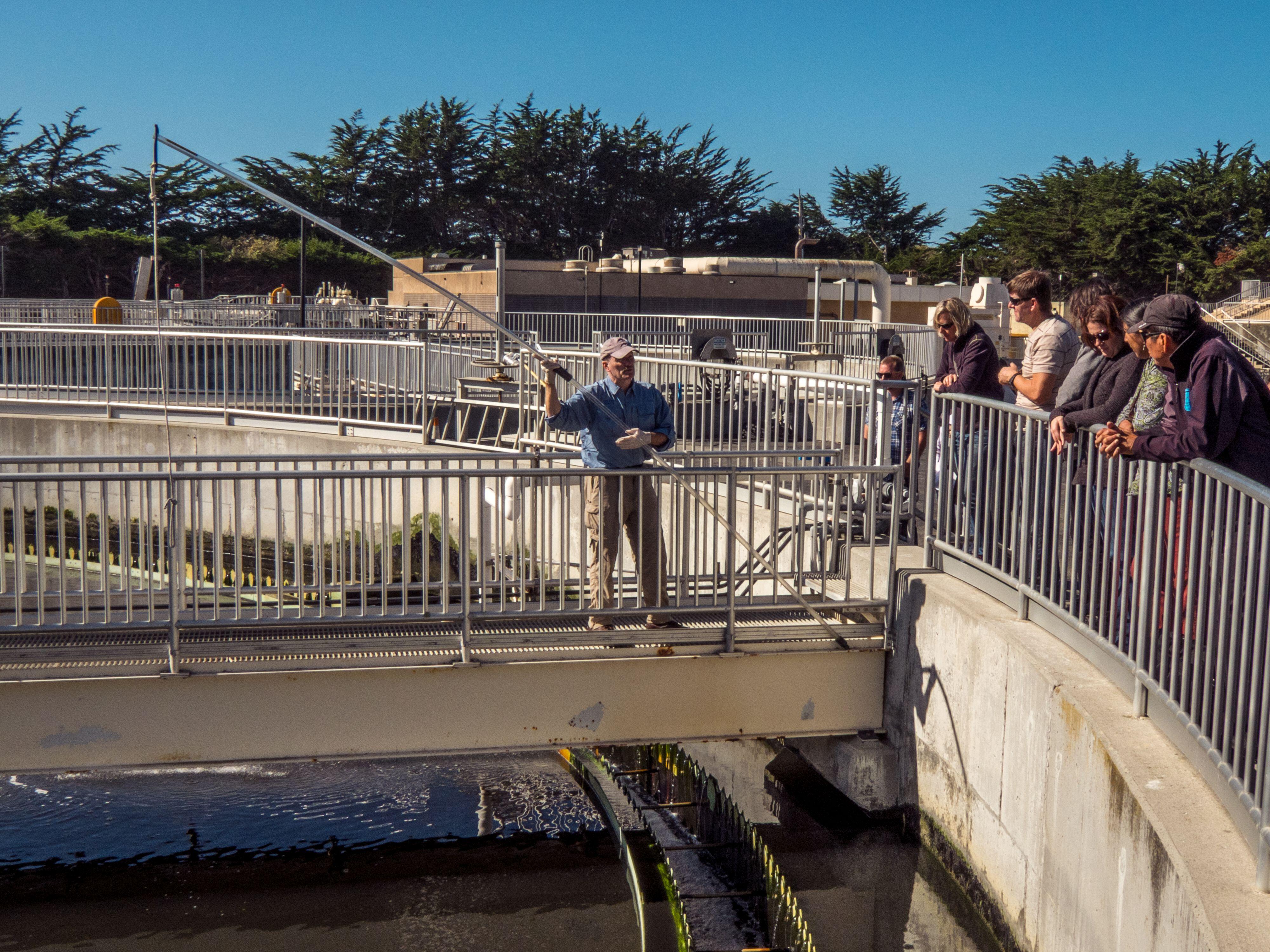 An operator at a wastewater treatment plant prepares to measure the depth of activated sludge in a wastewater clarifier.