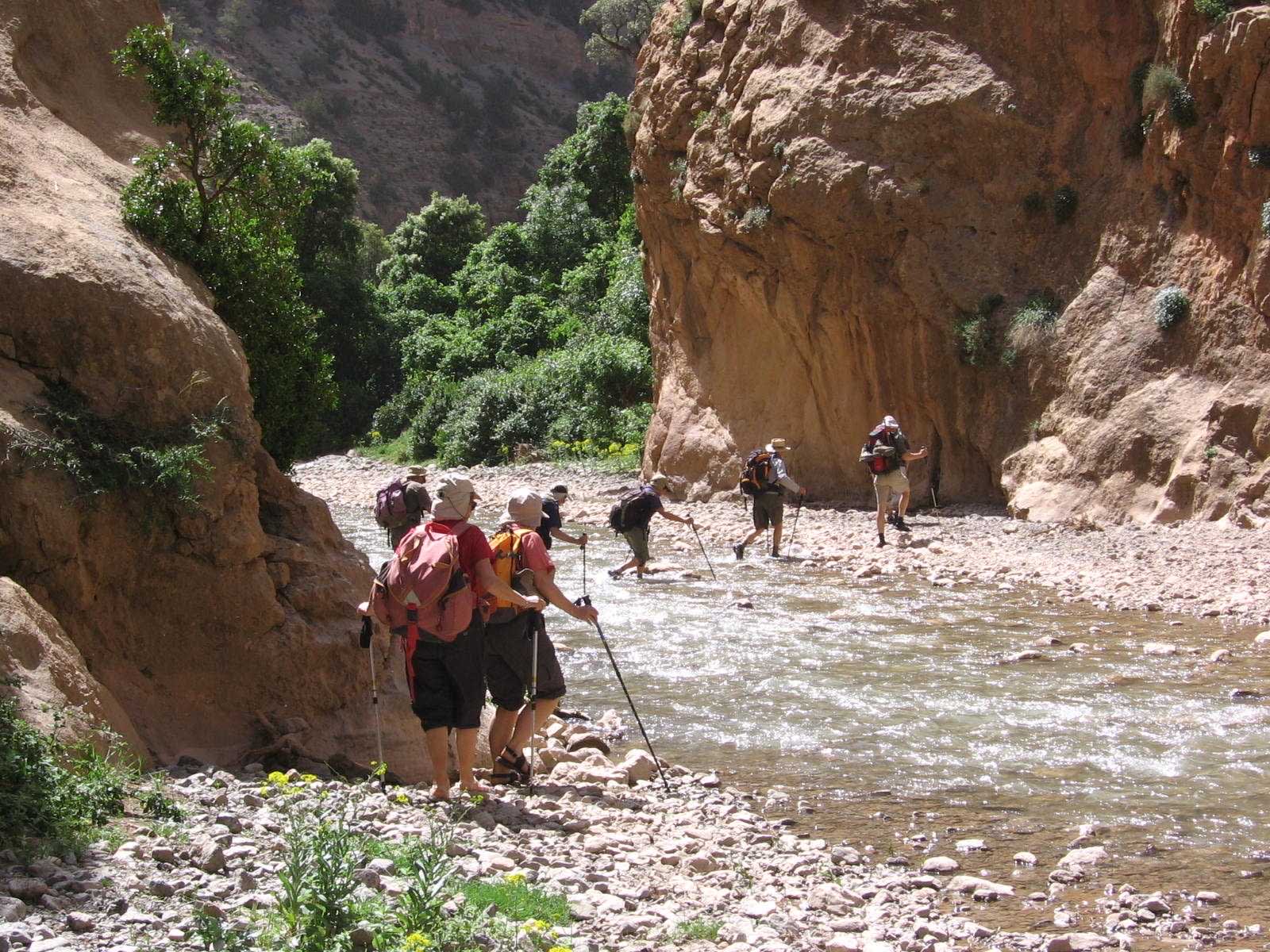 Randonneurs traversant un torrent dans les gorges du Haut Atlas Central