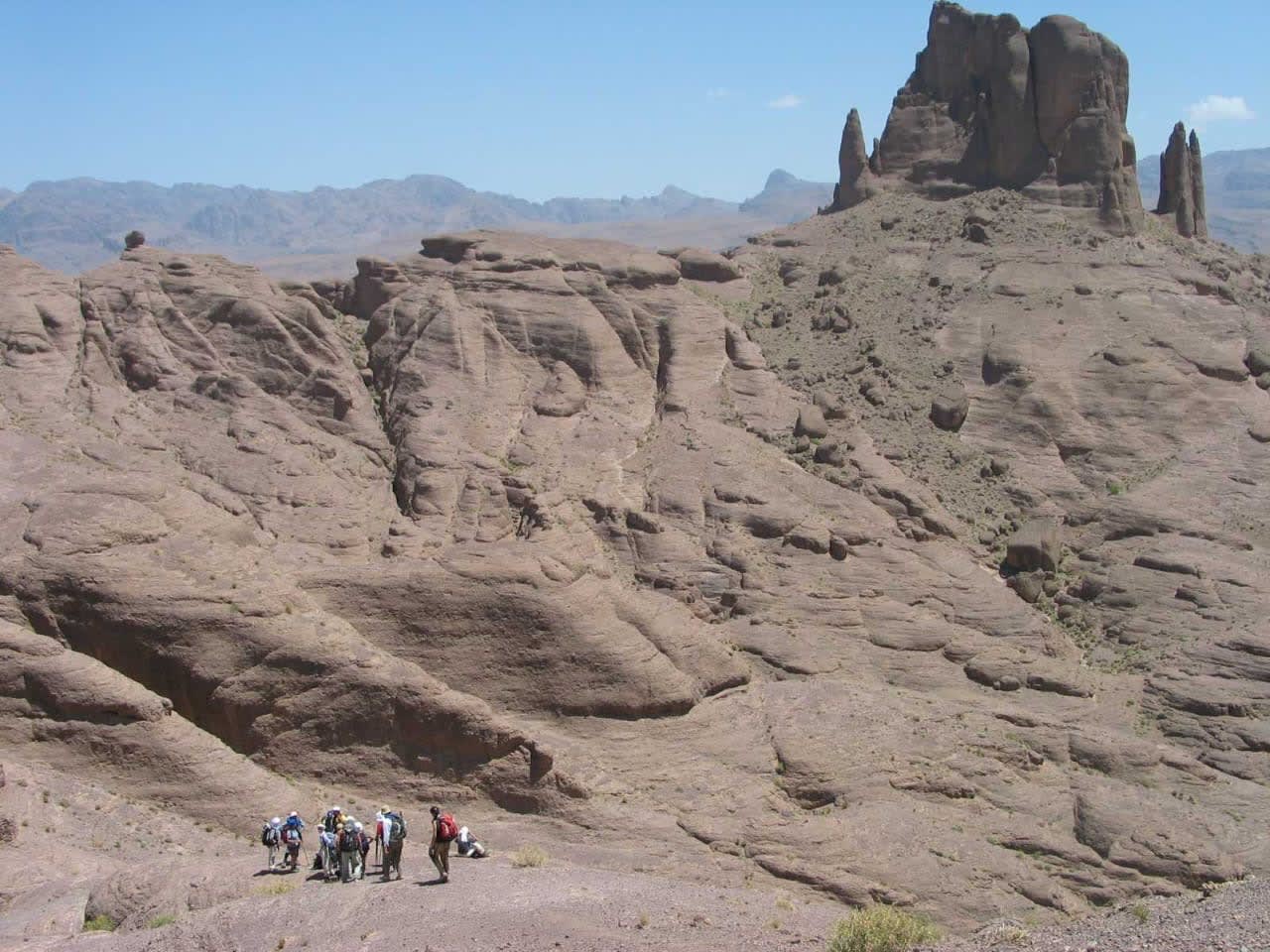 Randonneurs au pied des formations rocheuses monumentales du Jbel Saghro