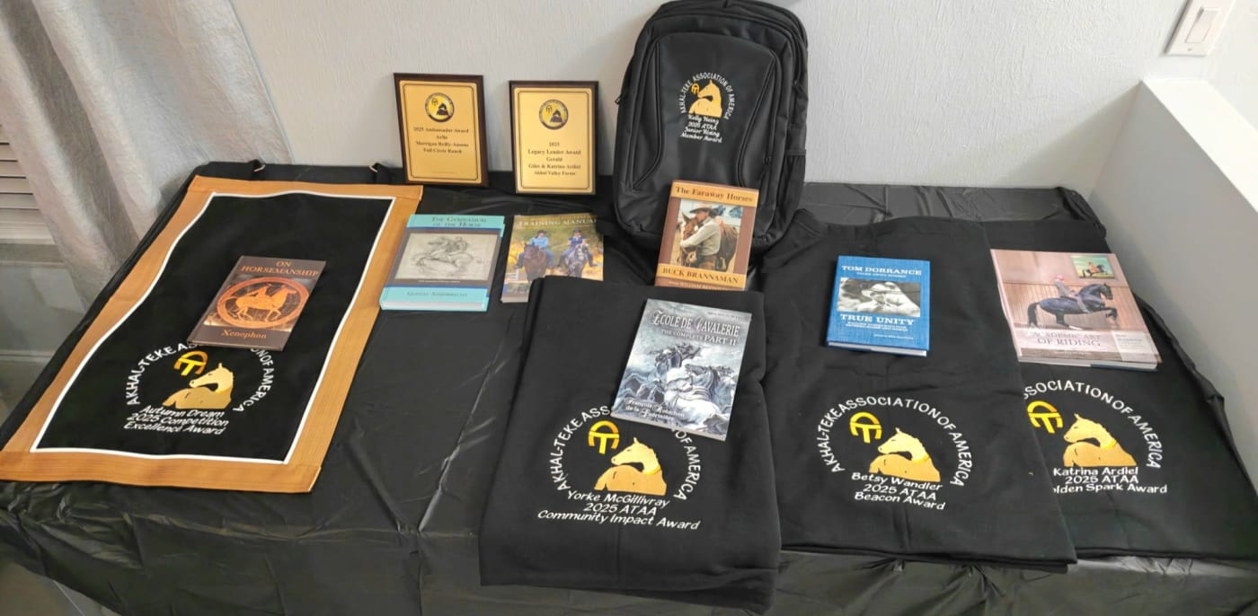 The 2025 ATAA awards laid out on a table: embroidered stall banner, towels and backpack, two plaques, and the books presented with each award