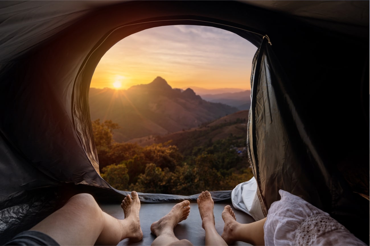 Pärchen auf einer Camper-Safari im Dachzelt genießen den Sonnenaufgang