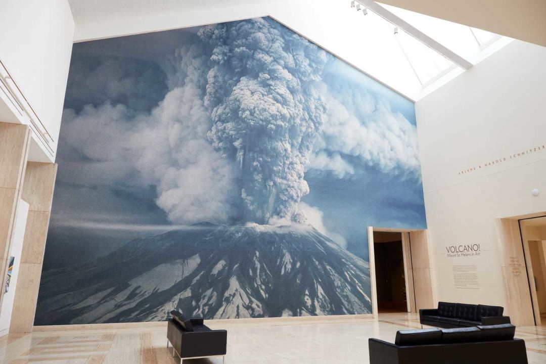A large photograph of Mount St. Helens erupting opens the Volcano! Mount St. Helens in Art exhibit at the Portland Art Museum