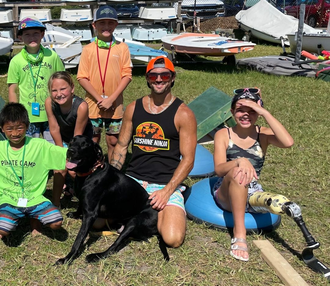 Kyle McCreight with his three-legged black lab Tre and children helped by Never Say Never Foundation, which supports kids who have had amputations and their families.