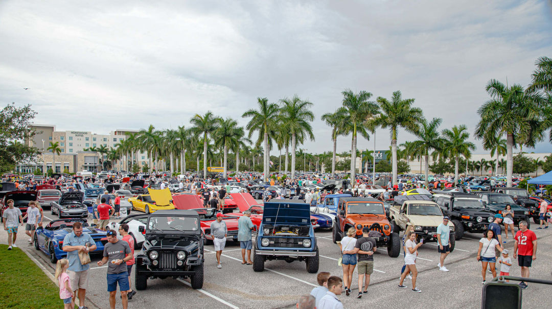 Car enthusiasts walk through the parking lot and enjoy the different cars.