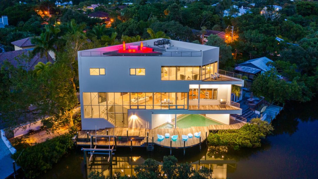 A drone shot of a luxury mansion with LED-lit glowing furniture.