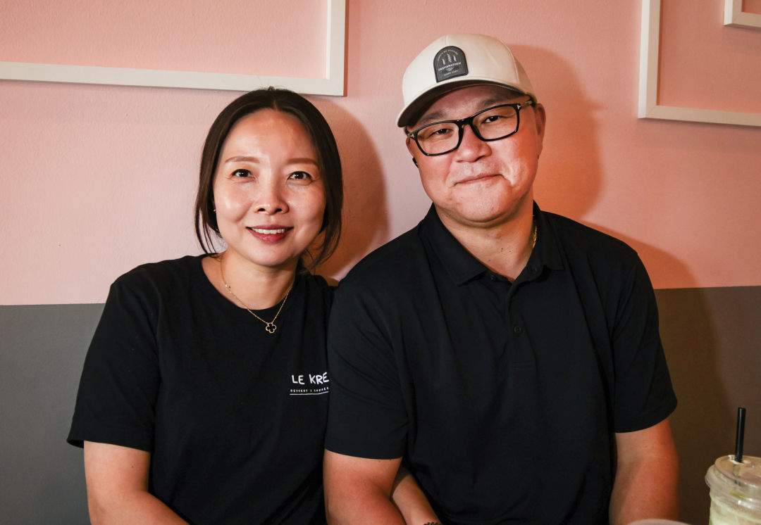 Sunny and Steve Hong sit in front of a pink wall at the cafe.