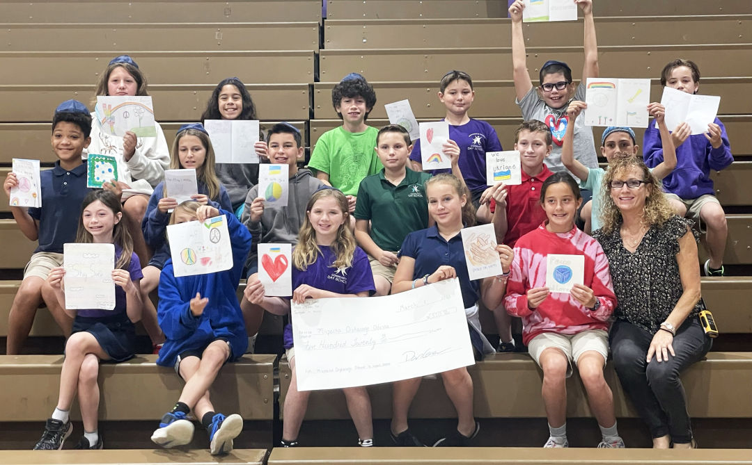 • Community Day School’s fifth grade students and teacher Joannie Bloch with the check that represents the funds the students raised.