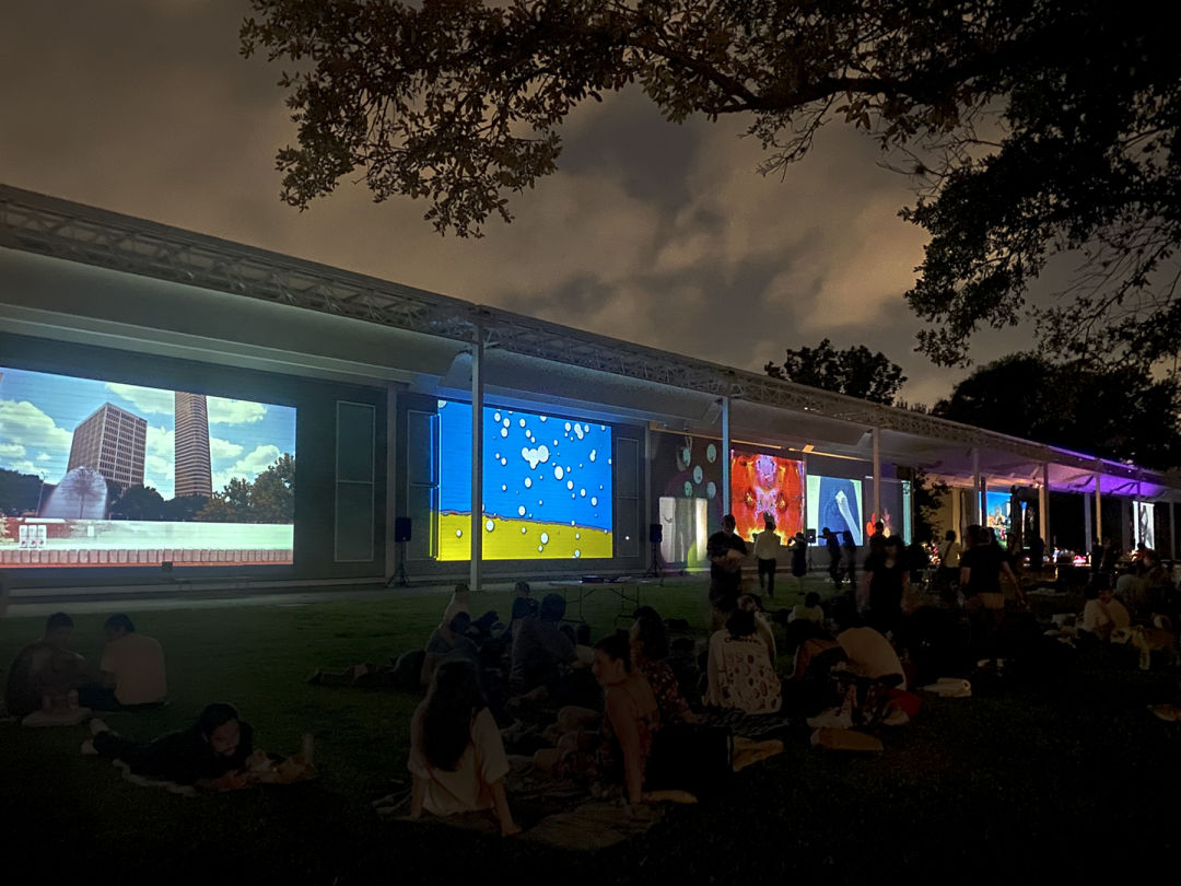 A museum with colorful films being projected onto the outer walls. It is dark outside.