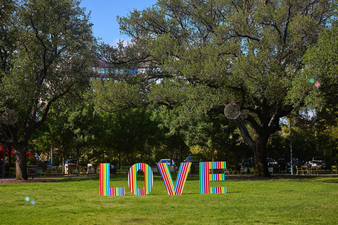 A rainbow sign reading "LOVE" set up in a park.