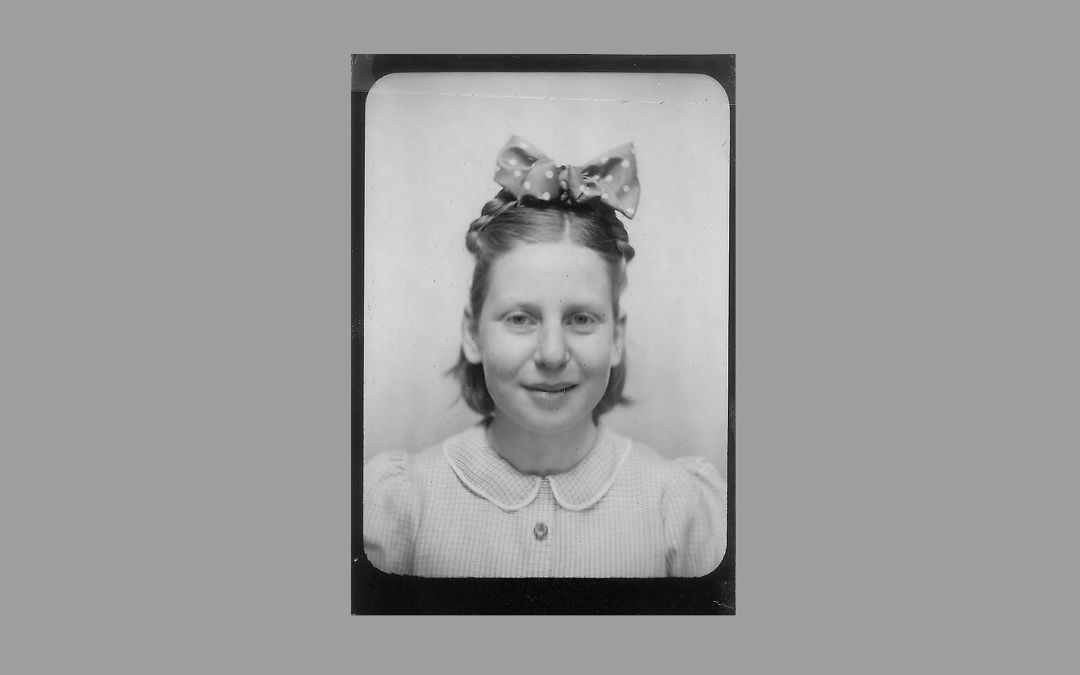 A black-and-white portrait of a girl with a large bow in her hair.