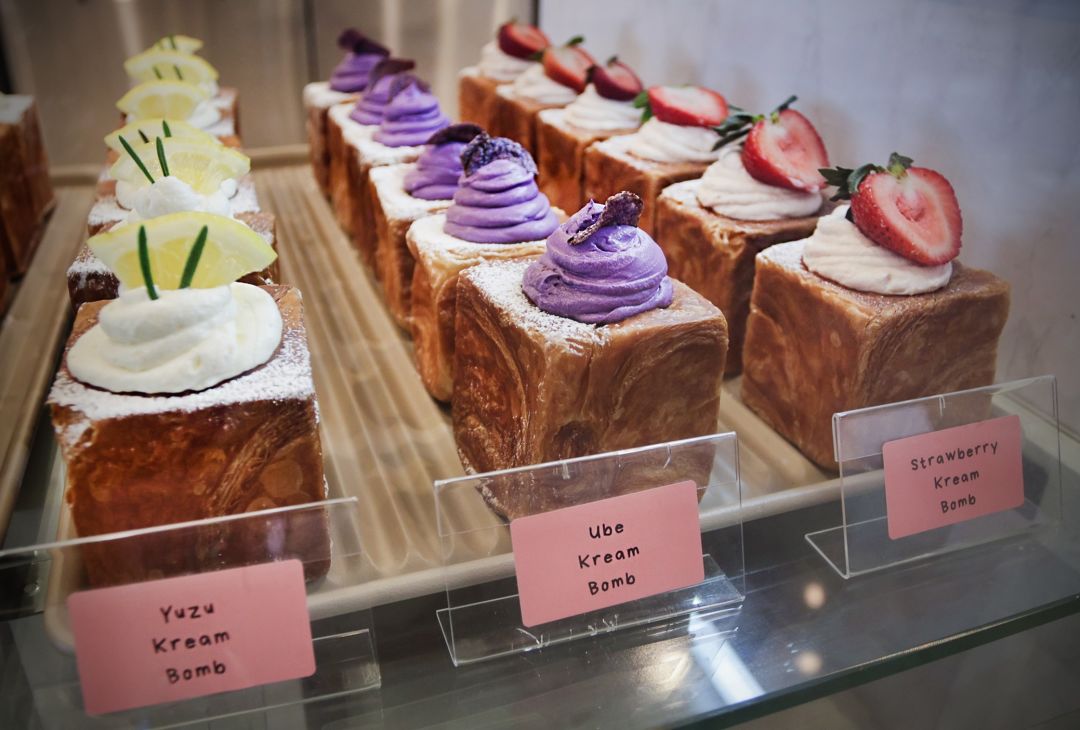 Cube croissants filled with bright purple ube cream sit in a display cast