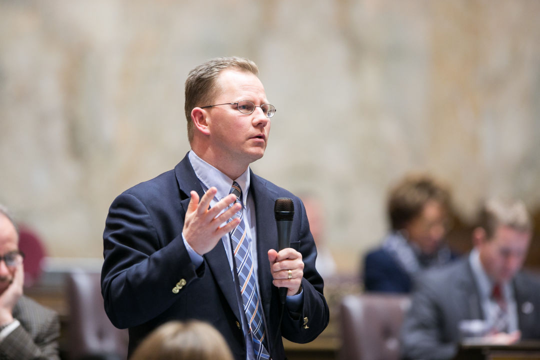 State schools superintendent Chris Reykdal stands with a microphone.