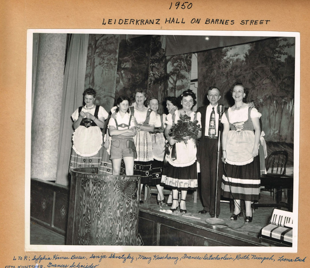 A black-and-white photo of people in liederhosen and dirndls, labeled as the Saengerbund from 1950.