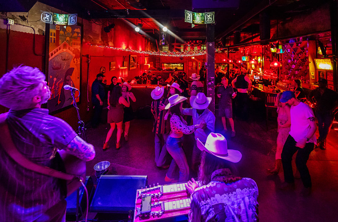 People in western wear dance at a bar.