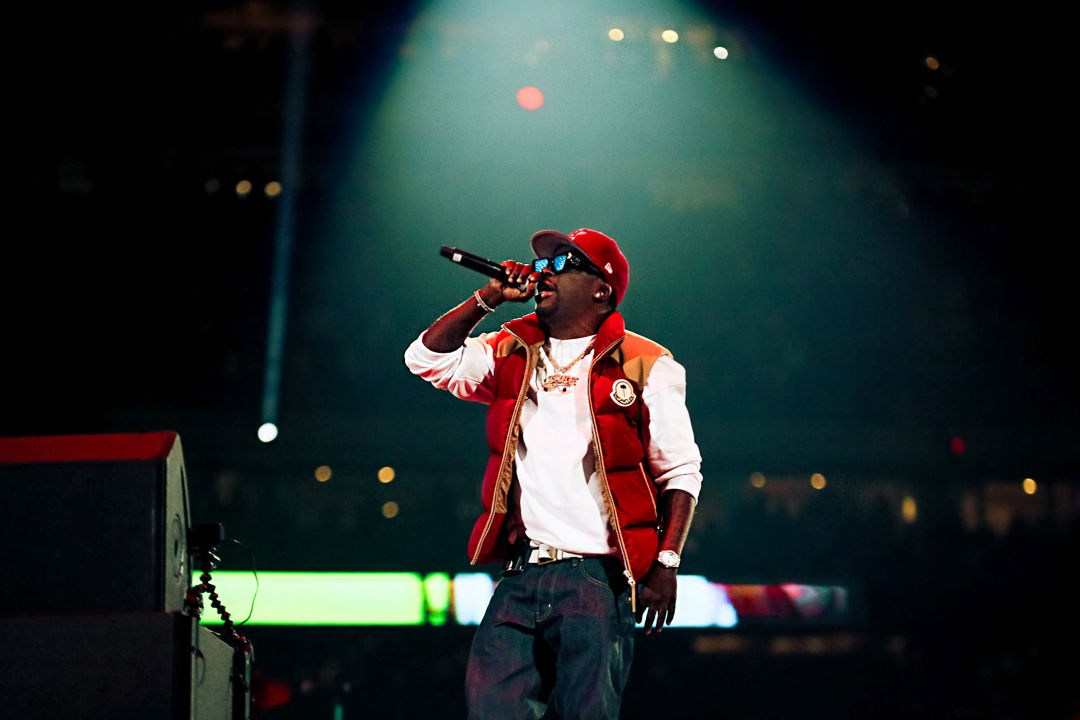 Spotlight shines down on rapper Lil' Keke, who is holding a mic and rapping