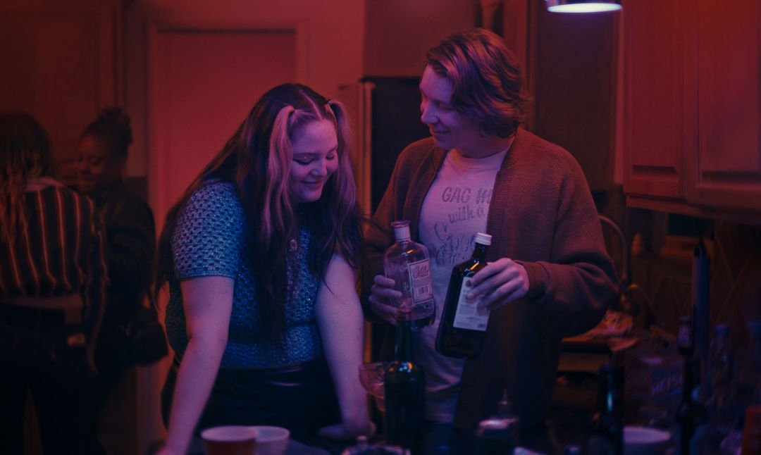 Meg Stalter stands with Thomas Mann in a kitchen while shooting Cora Bora.