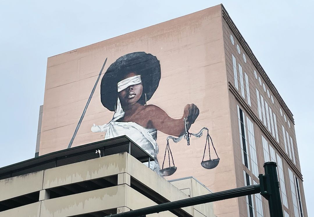 A mural of a Black woman dressed as lady justice.