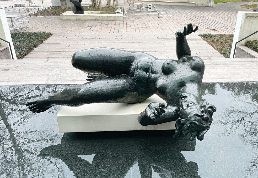 A dramatic sculpture of a naked woman falling sideways into a pool.