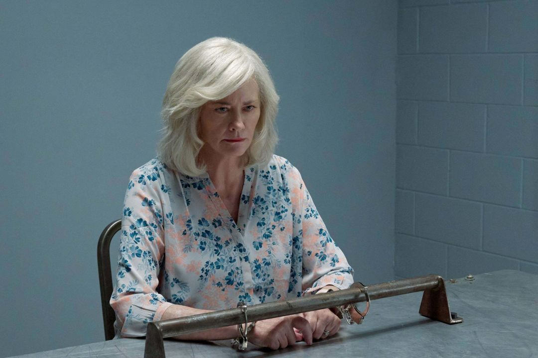 Actor Cybill Shepherd wearing handcuffs and seated in an interrogation room
