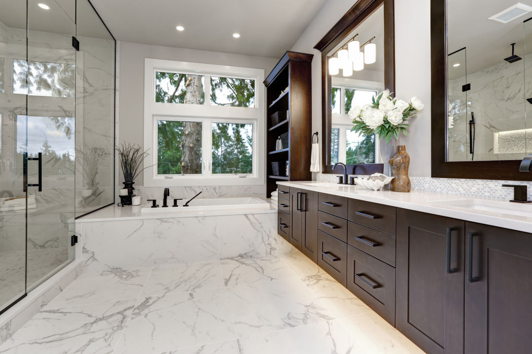 A renovated bathroom with dark drawers and white marble tiles.