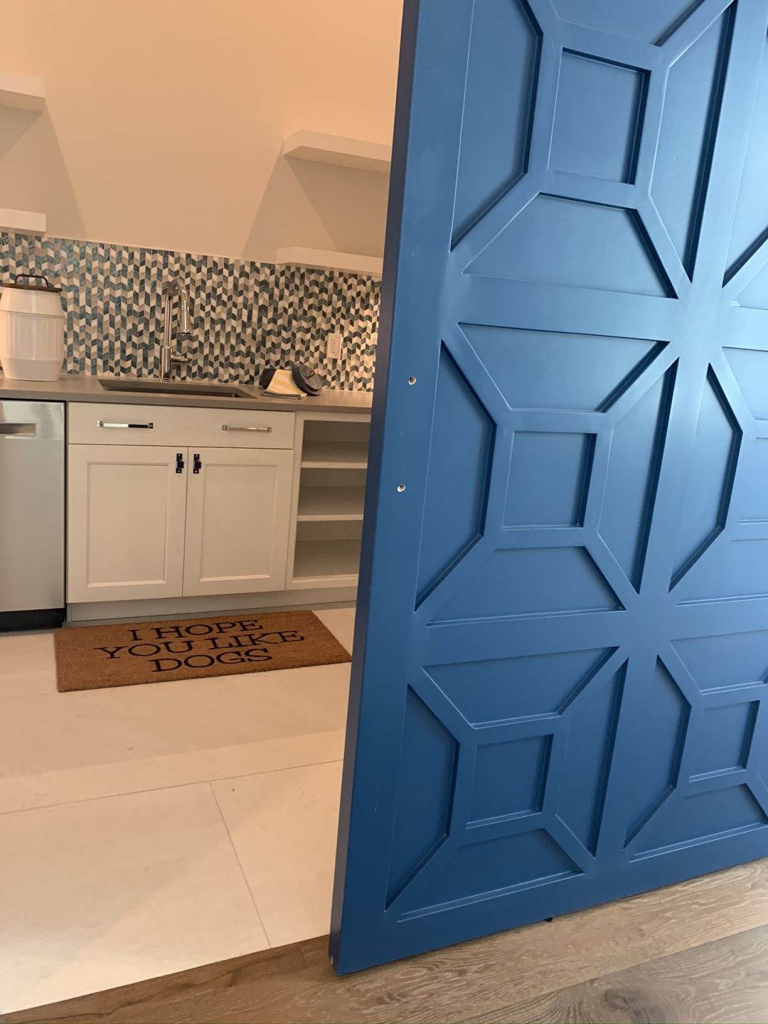 A blue farm door sports wood trimming in geometric shapes.