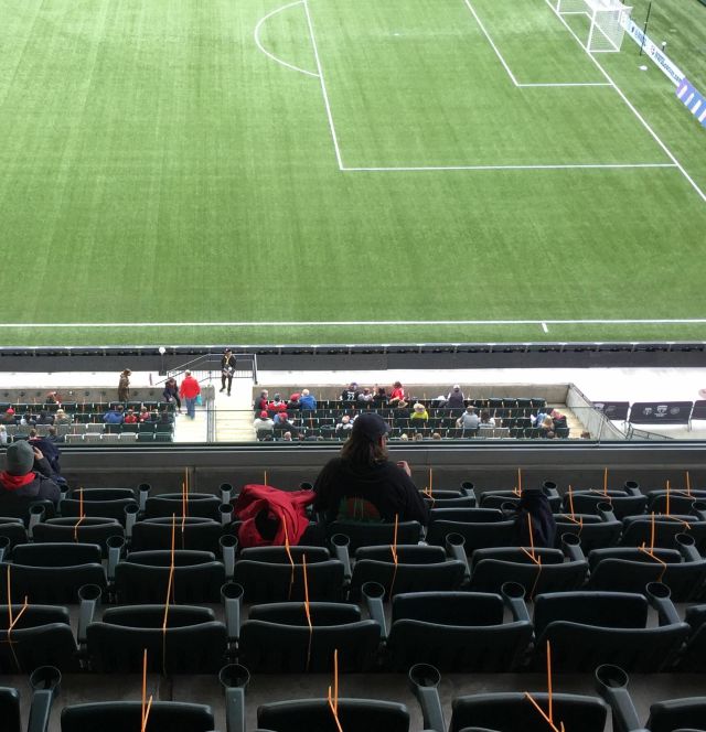 Orange zip ties on stadium seats, with the soccer pitch visible below