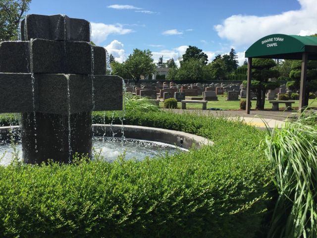 A stone fountain with a chapel awning and gravestones in the background