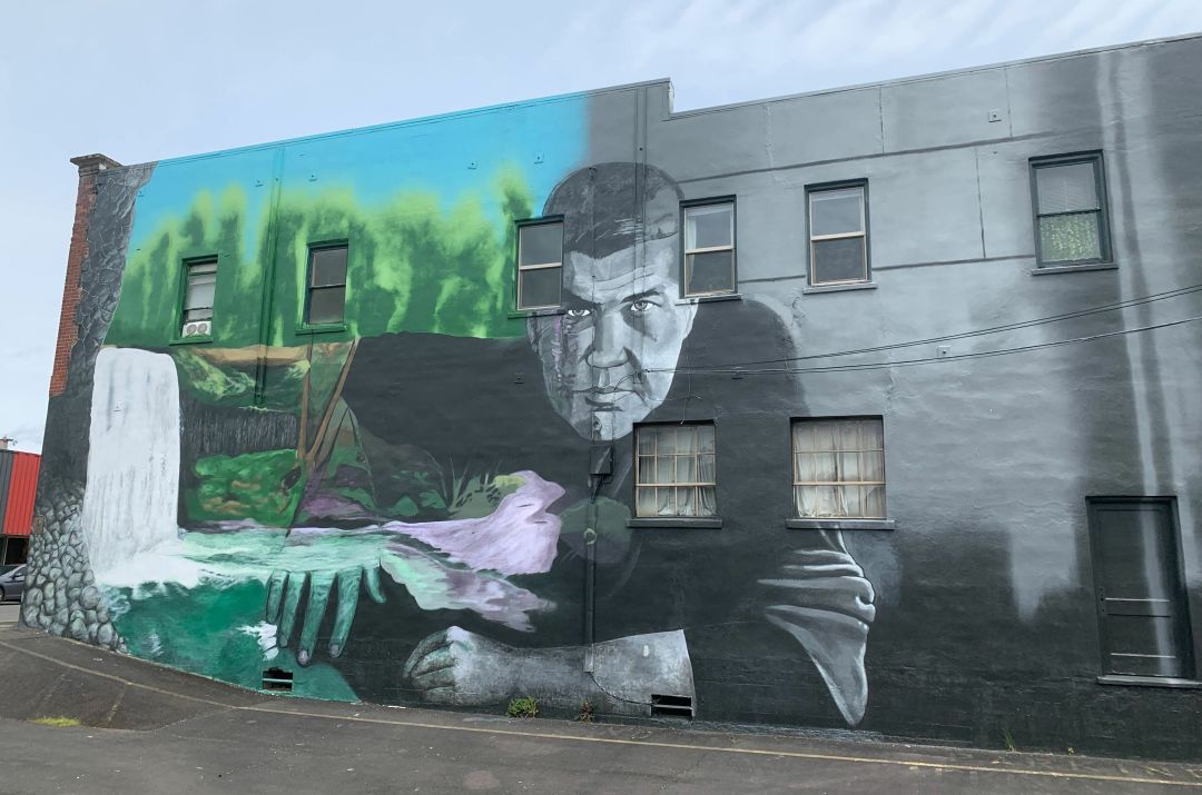face of writer Raymond Carver on a multistory building, with evergreens and a waterfall pictured on one side