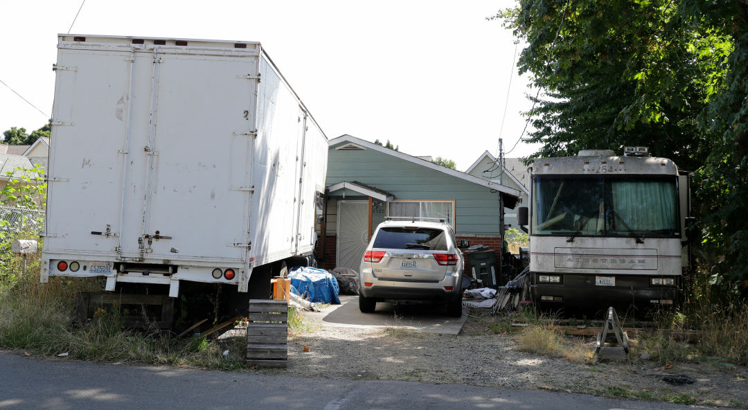 Beacon Hill home of Paige Thompson with three a furniture truck, a Jeep, and an Airstream outside.