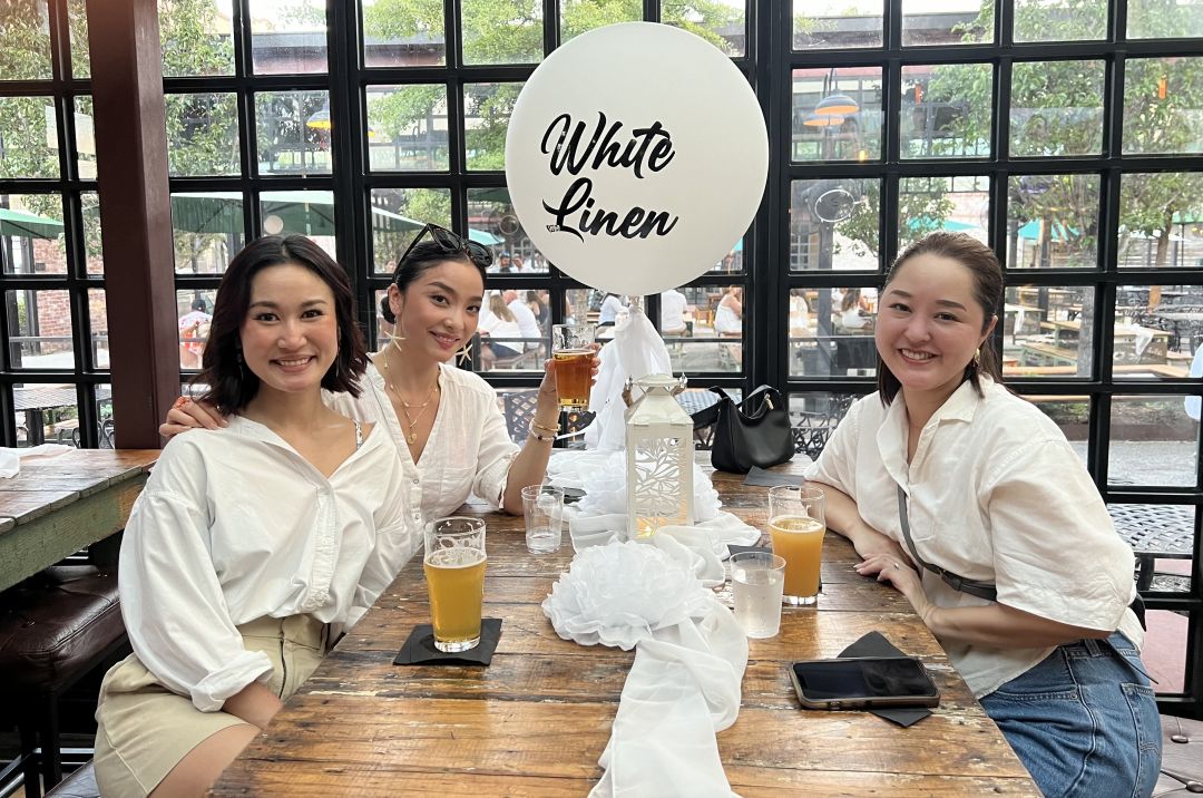 Three people wearing white sitting at a biergarten table.