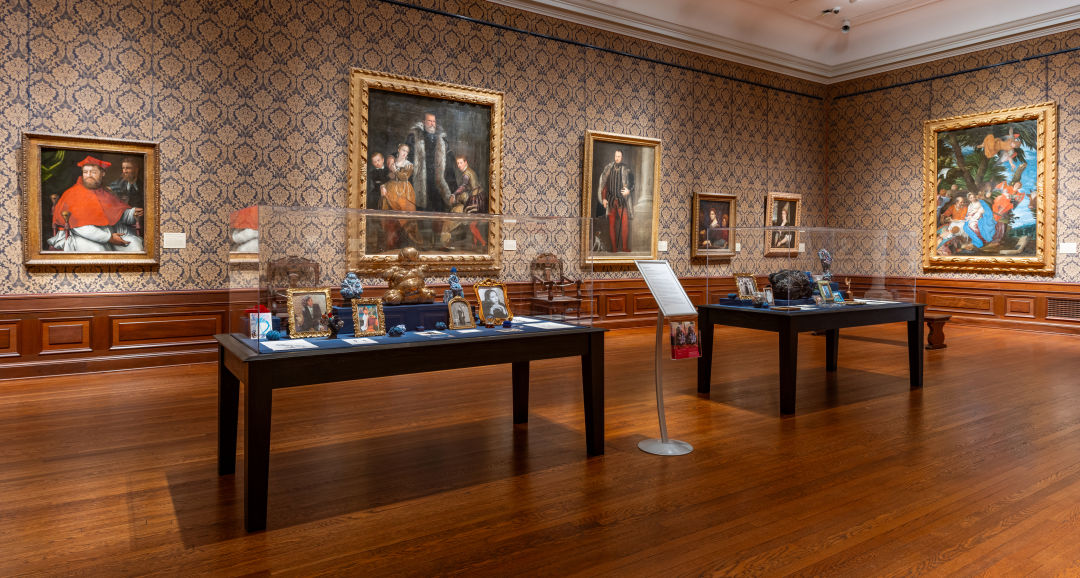 A display featuring framed photos of Smith’s family juxtaposed with works by Old Masters in the background.