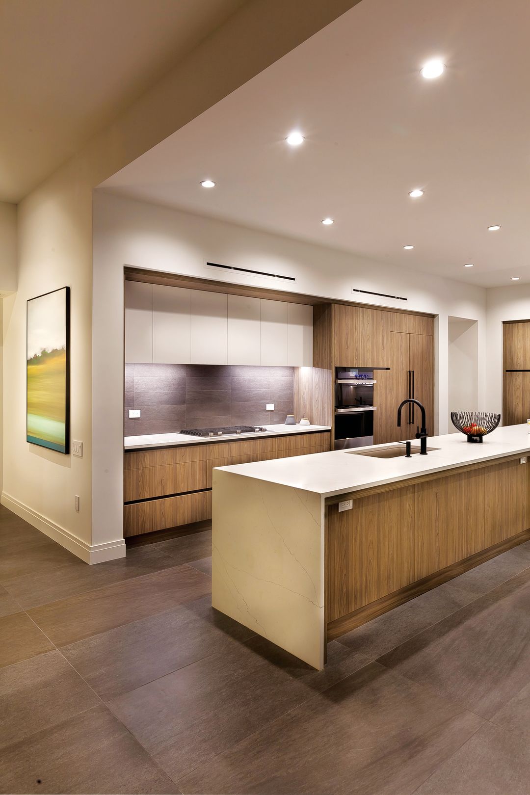 The absence of cabinet hardware and a hidden range hood contribute to the sleek feel in the kitchen.