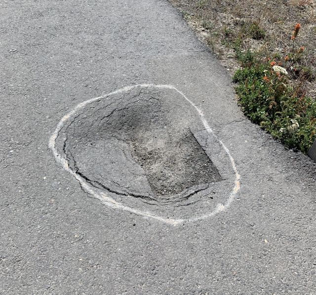 A depression in a paved surface marked with chalk