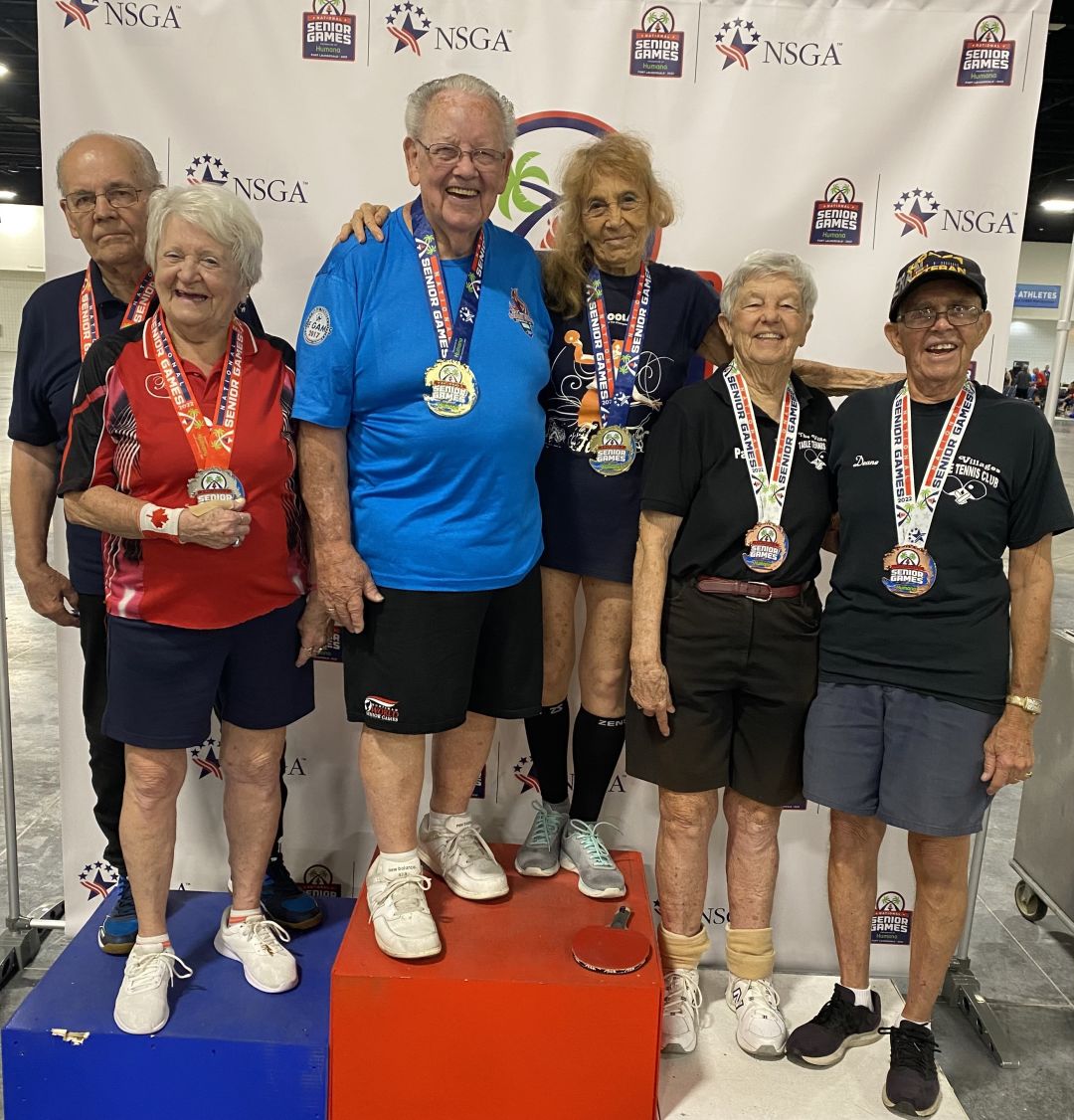 John Shultz (in light blue) posing with his medal