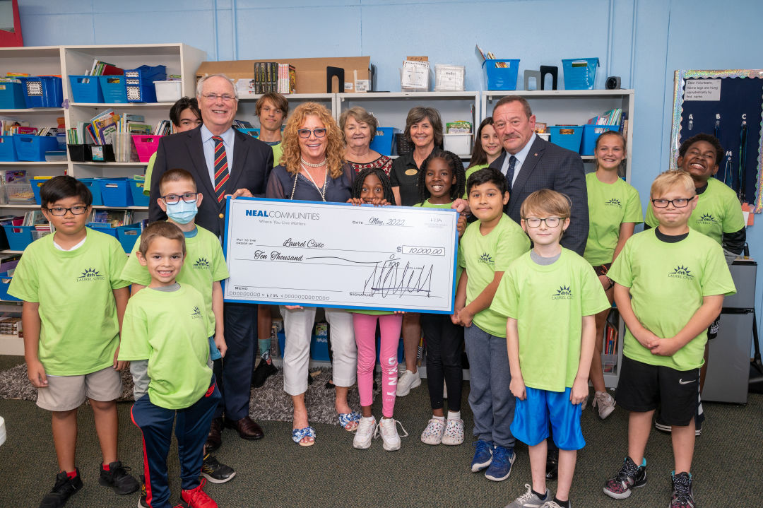 From left to right, Pat Neal, founder and chairman of Neal Communities, Valerie Fox of Neal Signature Homes, Laurel Civic Agency’s Board Member Secretary Suzanne Barksdale, Board Treasurer Terri Ramey and Executive Director Peter M. Casamento pose with a donation check alongside youth participating in Laurel Civic Agency’s programs.