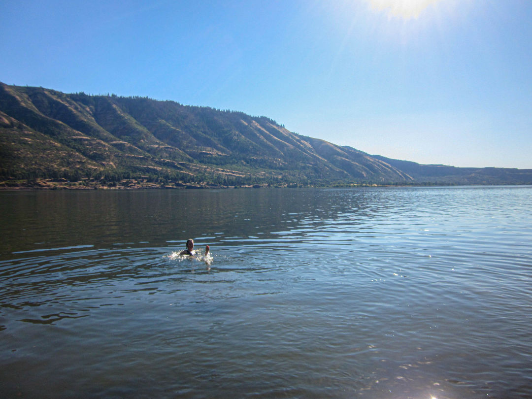 a person splashing in the water in a wide, calm river