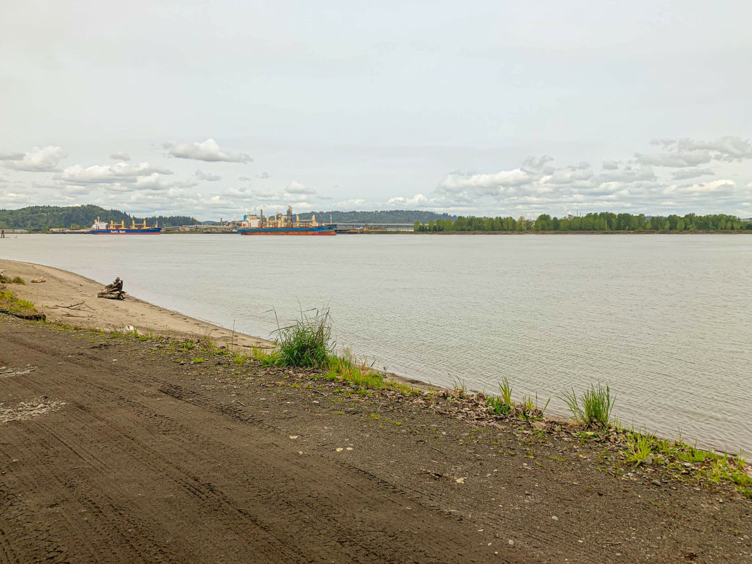 dirt road, sand, river, container ships in background