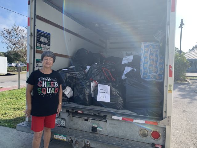 Volunteer who adopted 72 kids poses by truck load of gifts.