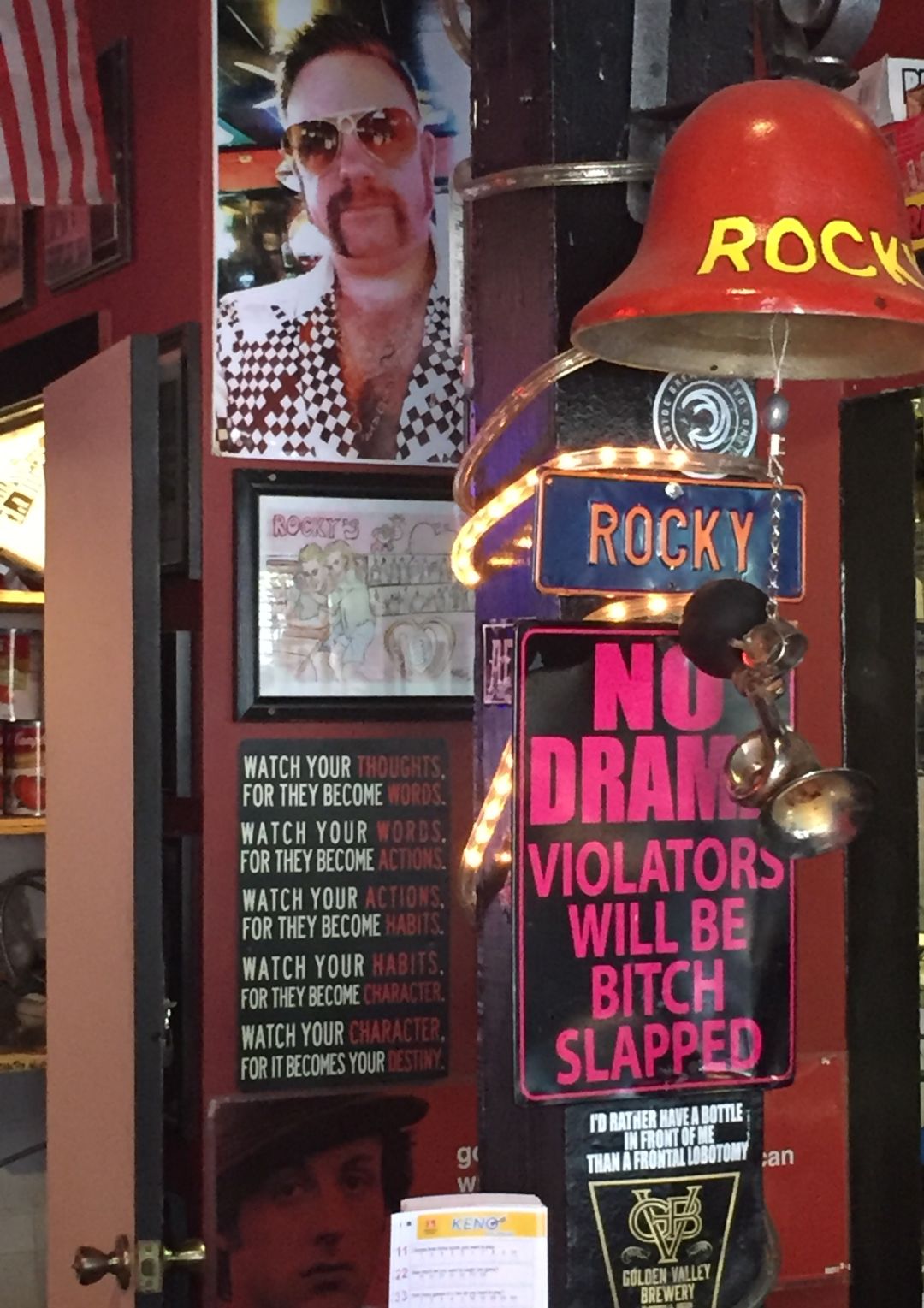 A column at the end of a bar decorated with signs, photos, and a bell