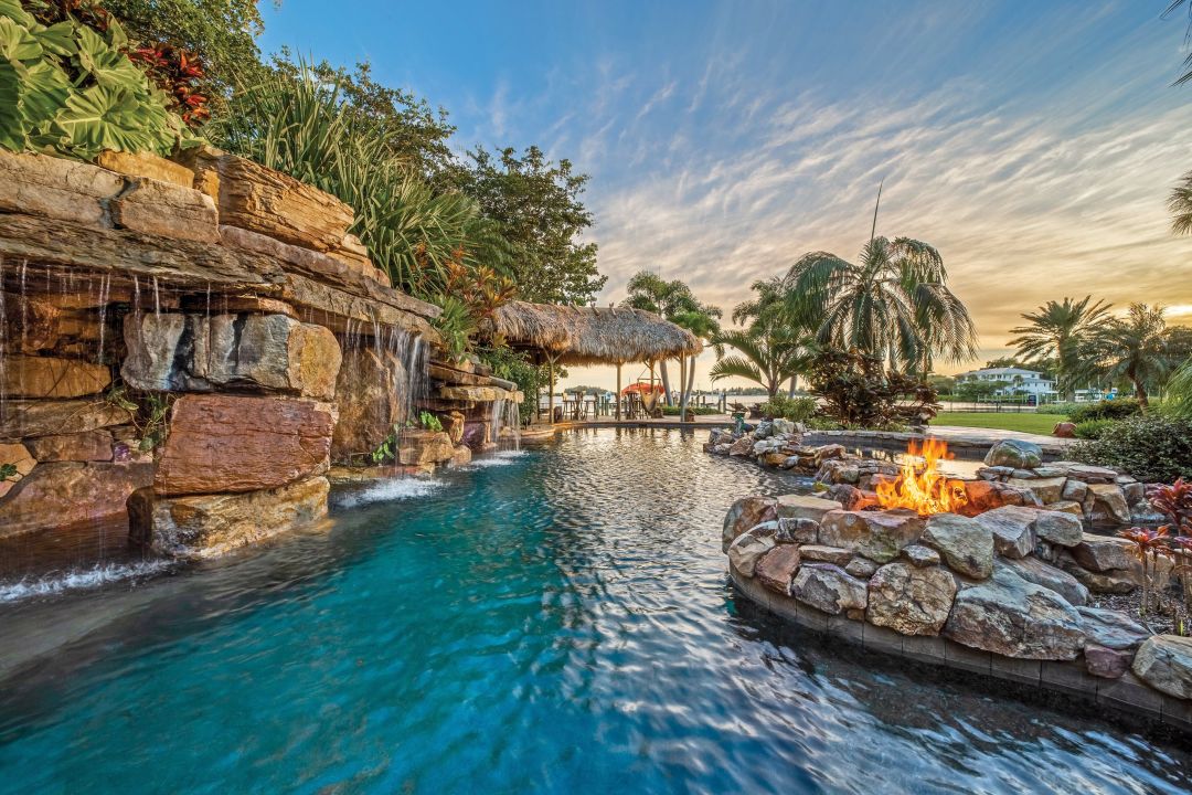 Natural boulders and rocks are layered to create the feel of a waterfall grotto. The pool below is deep enough for diving, and a fire element adds drama.