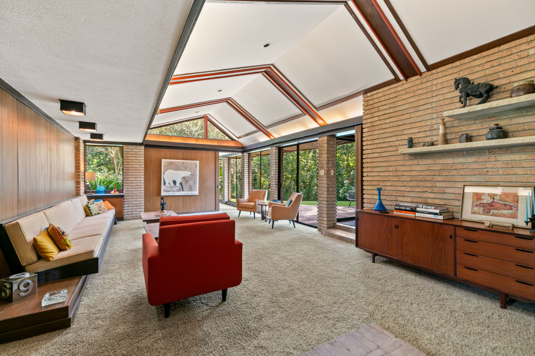 A midcentury modern living room with lots of natural light pouring in from large windows.