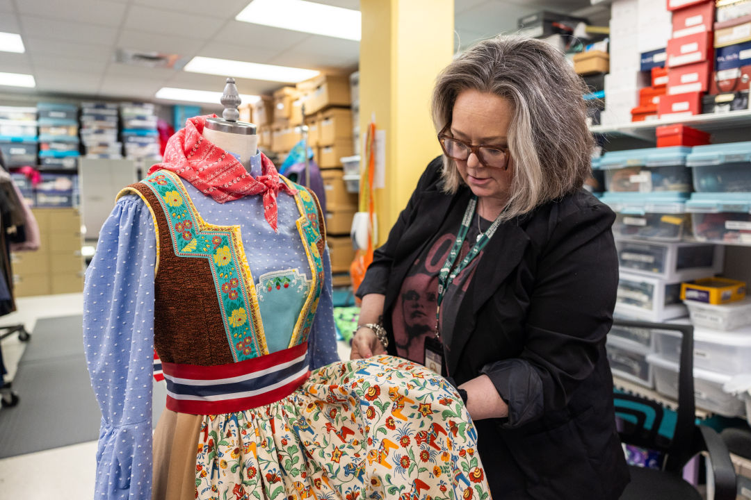 A woman in a costume shop inspects the skirt of a traditional Swedish dress.