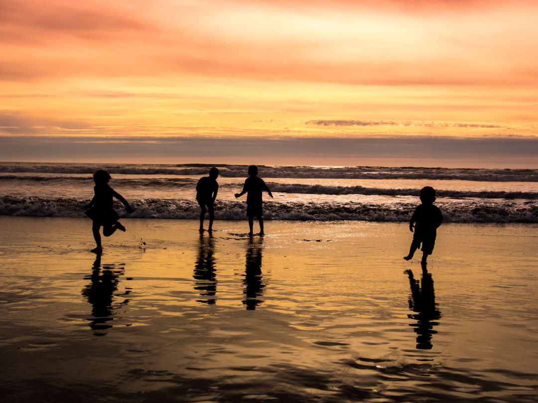 Children on a beach at sunset