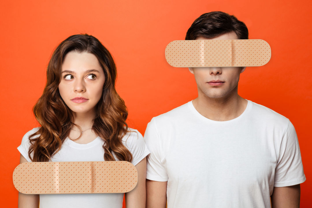 A woman and a man with Band-Aids covering her breasts and his eyes.