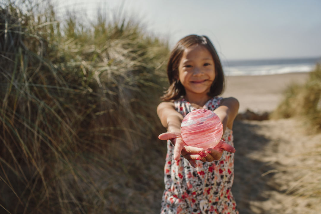 Girl with a glass float at the beach