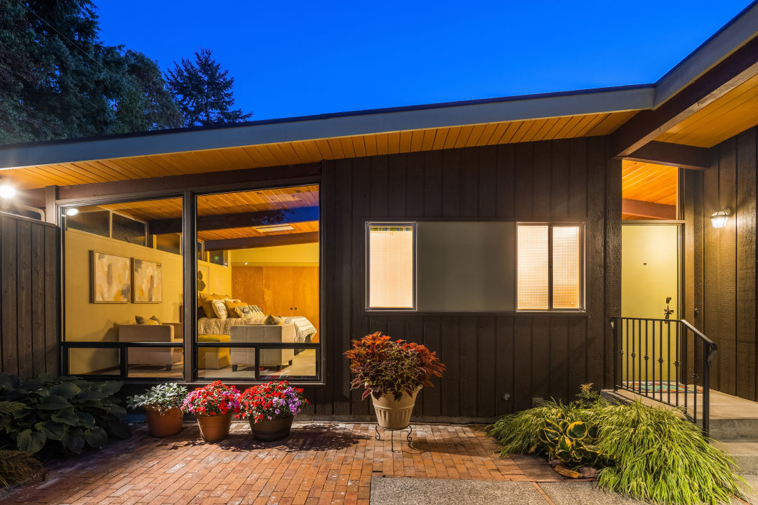 The view of a home from a courtyard. There's a door to the right, and a tall window to a bedroom on the left.