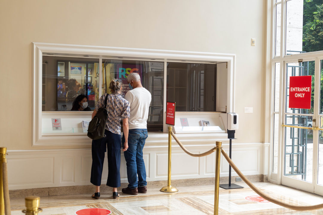 Two people check in at the Portland Art Museum admissions window