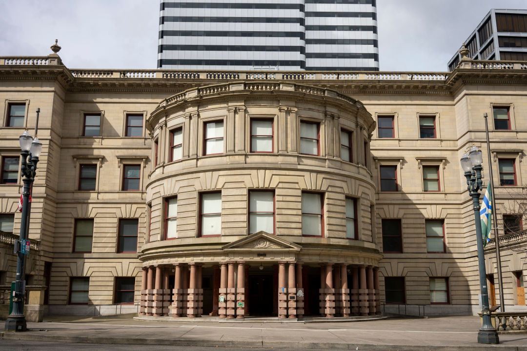 Four-story stone building with three-story rotunda on the facade, with some of a taller building visible behind